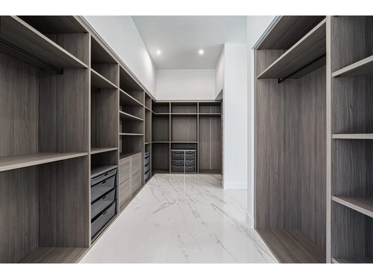 Modern walk-in dressing room with dark built-in shelving and marble floor